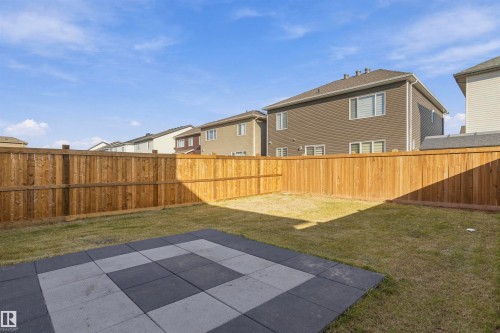 Backyard featuring a wood privacy fence, a grass lawn, and a square concrete paver patio - 2045 209A St Nw, Edmonton, AB 