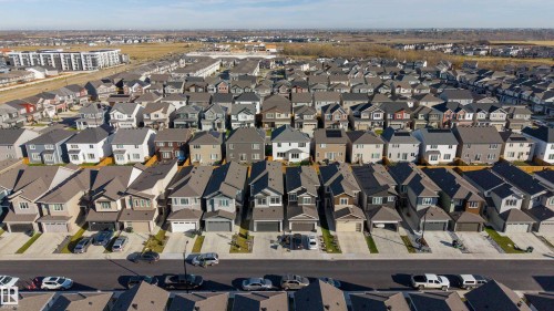 Aerial perspective of a suburban neighborhood featuring residential homes with multi-gabled rooflines, attached garage structures, paved private driveways, and consistent sidewalk infrastructure - 2045 209A St Nw, Edmonton, AB 