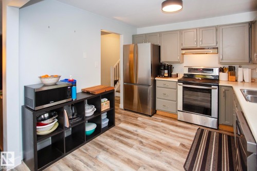 Kitchen featuring gray cabinetry, stainless steel appliances, wood-finish flooring, and a ceiling-mounted light fixture - 8 Ash Crescent, St. Albert, AB 