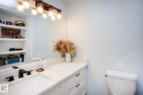 White vanity with shaker-style cabinetry, matte black hardware, integrated sink, and a large mirror - 8 Ash Crescent, St. Albert, AB 