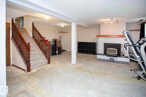 Spacious room with a brick fireplace, wood mantel, and wood-burning insert - 8 Ash Crescent, St. Albert, AB 