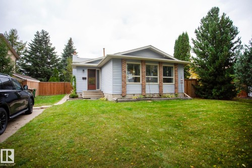 Siding exterior with brick accents, expansive front lawn, paved driveway, mature trees, and wooden fencing - 8 Ash Crescent, St. Albert, AB 