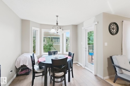 Bay window, wood-finish flooring, multi-light hanging chandelier, and glass-paneled exterior door - 4 1920 Millwoods Rd E Nw, Edmonton, AB 