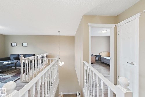 White spindle staircase railing, neutral wall tones, wood-finish flooring, and multi-paneled interior door - 4 1920 Millwoods Rd E Nw, Edmonton, AB 