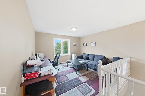 Interior space featuring neutral wall paint, a double-pane window, and a white baluster railing - 4 1920 Millwoods Rd E Nw, Edmonton, AB 