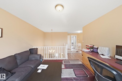 Open interior space featuring wood-finish flooring, white wooden balustrade railings, and integrated ceiling lighting - 4 1920 Millwoods Rd E Nw, Edmonton, AB 