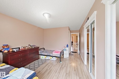 Room interior featuring wood-finish flooring, mirrored closet doors, and crown molding - 4 1920 Millwoods Rd E Nw, Edmonton, AB 