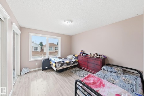 Neutral-toned interior featuring wood-finish flooring, a large picture window, and mirrored sliding closet doors - 4 1920 Millwoods Rd E Nw, Edmonton, AB 