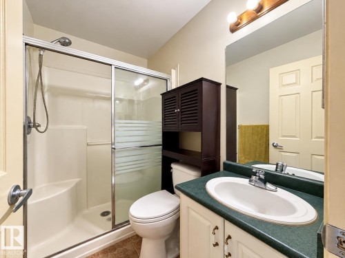 Shower enclosure featuring sliding glass doors and an integrated seat, vanity with a solid-surface countertop, and an oval undermount sink - 4 1920 Millwoods Rd E Nw, Edmonton, AB 