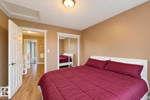 Room featuring wood-finish flooring, mirrored sliding closet doors with white trim, and a ceiling-mounted light fixture - 4 1920 Millwoods Rd E Nw, Edmonton, AB 
