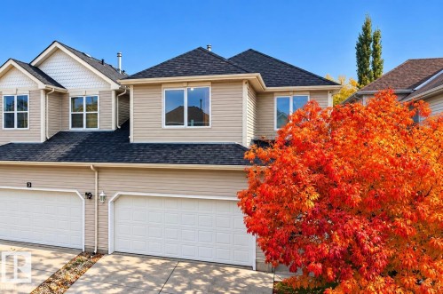 Multi-level exterior featuring light-toned horizontal siding, decorative shingle gables, asphalt shingle roofing, and attached two-car garages - 4 1920 Millwoods Rd E Nw, Edmonton, AB 