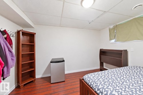 Room featuring wood-finish flooring, a drop ceiling with integrated flush-mount lighting, and a high-set window - 4 1920 Millwoods Rd E Nw, Edmonton, AB 