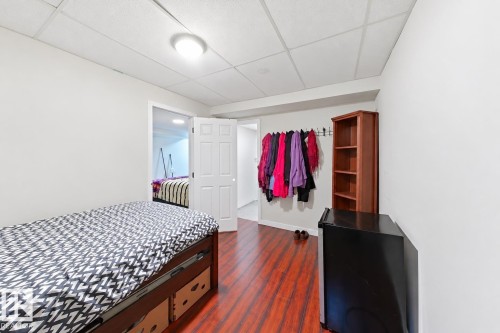 Interior room featuring wood-finish flooring, a six-panel door, and a textured drop ceiling with a flush-mount light fixture - 4 1920 Millwoods Rd E Nw, Edmonton, AB 
