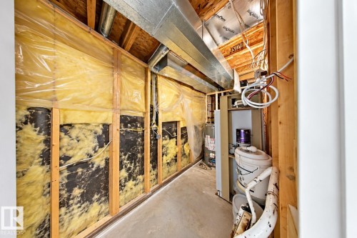 Utility area featuring exposed timber framing, fiberglass batt insulation, galvanized metal ductwork, and a concrete floor - 4 1920 Millwoods Rd E Nw, Edmonton, AB 