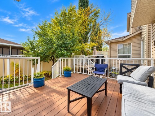 Rear exterior deck featuring composite decking, white metal railing, and privacy fencing - 4 1920 Millwoods Rd E Nw, Edmonton, AB 