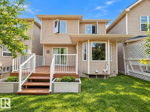 Rear exterior featuring horizontal lap siding, an elevated wood-tone deck with white railing, built-in wooden planters, and a multi-paneled bay window - 4 1920 Millwoods Rd E Nw, Edmonton, AB 