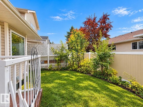 Backyard featuring a manicured lawn, white lattice and solid panel perimeter fencing, and mature trees - 4 1920 Millwoods Rd E Nw, Edmonton, AB 