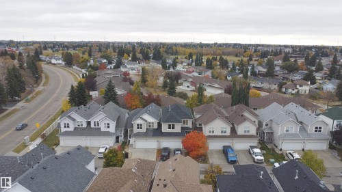 Aerial perspective featuring multi-story residential architecture with pitched shingle roofing, multi-car garage configurations, and paved private driveways - 4 1920 Millwoods Rd E Nw, Edmonton, AB 