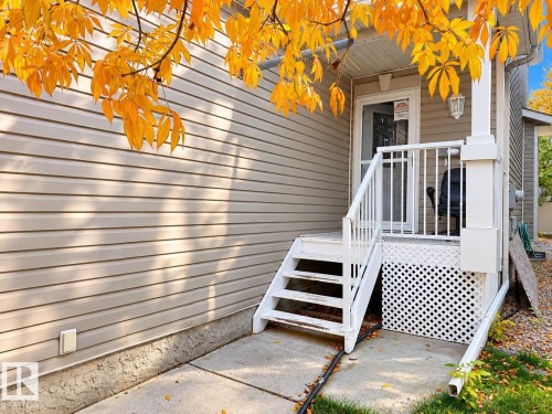 Exterior entrance featuring horizontal vinyl siding, white metal railings, elevated steps, and a decorative lattice skirt - 4 1920 Millwoods Rd E Nw, Edmonton, AB 