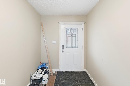 Exterior door featuring a glass inset with decorative leaded detail, crisp white casing, and electronic keypad entry lock - 4 1920 Millwoods Rd E Nw, Edmonton, AB 