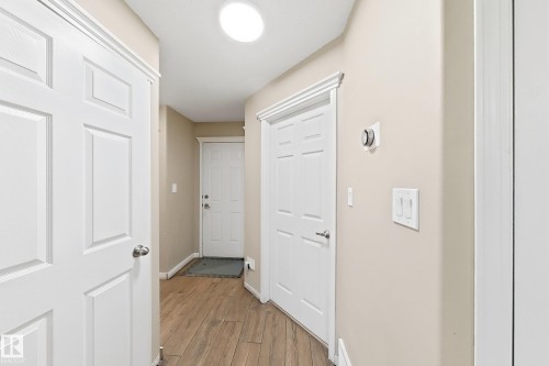 Entryway featuring wood-finish flooring, six-panel interior doors, crisp white door casings, and a flush-mount ceiling light fixture - 4 1920 Millwoods Rd E Nw, Edmonton, AB 