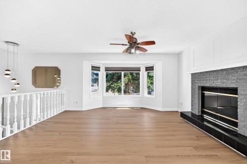Bay window, wood-finish flooring, contemporary chandelier, stone-clad fireplace, and ceiling fan - 3924 26A Avenue Nw, Edmonton, AB 