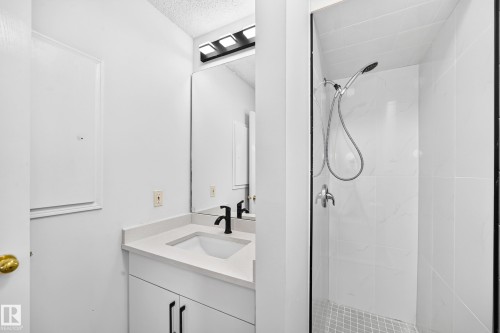 Vanity with a light-toned countertop, integrated sink, and matte black faucet - 3924 26A Avenue Nw, Edmonton, AB 