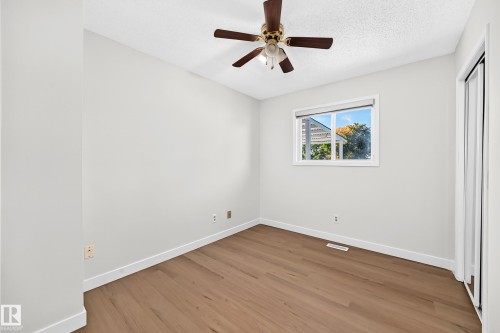 Wood-finish flooring, ceiling fan with integrated lighting, white trim, and a window with roller shades - 3924 26A Avenue Nw, Edmonton, AB 