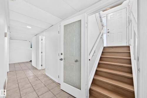 White interior doors, wood-finish staircase, tile flooring, and recessed ceiling lighting - 3924 26A Avenue Nw, Edmonton, AB 