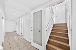 White interior doors, wood-finish staircase, tile flooring, and recessed ceiling lighting - 