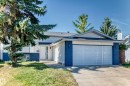 Front exterior featuring white siding, a contrasting dark blue lower facade, an attached garage with a concrete driveway, a front entrance with a white door, and a mature tree - 3924 26A Avenue Nw, Edmonton, AB 