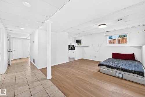 Spacious open-concept room with light wood-finish flooring, recessed lighting, and a window providing natural light - 3924 26A Avenue Nw, Edmonton, AB 