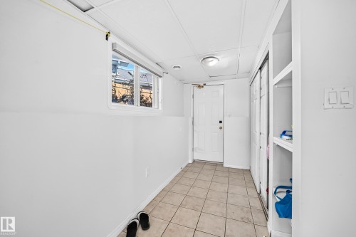 Tiled flooring, white painted walls, a window, built-in shelving, and a door with overhead lighting - 3924 26A Avenue Nw, Edmonton, AB 