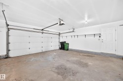 Attached garage with a white sectional door, automatic garage door opener, interior access door, and wall-mounted shelving brackets - 