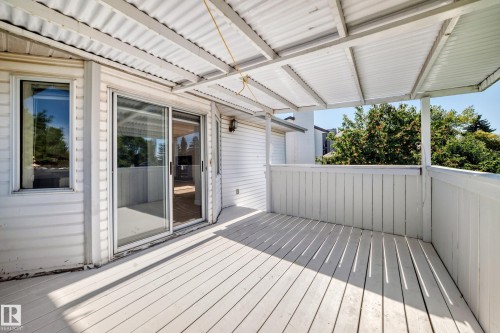 Outdoor deck featuring white painted wood plank flooring, a white corrugated metal roof, a white wood railing, and vinyl siding - 3924 26A Avenue Nw, Edmonton, AB 