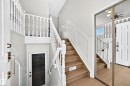 Hardwood stairs with white balusters, wainscoting detailing, and a mirrored closet door - 3924 26A Avenue Nw, Edmonton, AB 