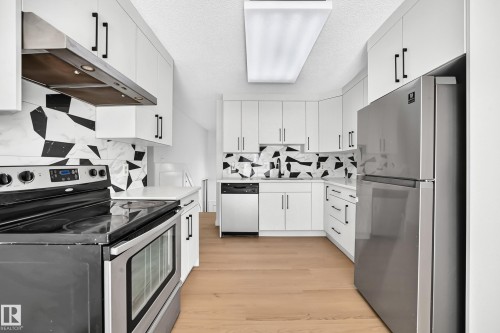 Kitchen featuring white cabinetry with dark pulls, stainless steel appliances, white countertops, and a patterned backsplash - 3924 26A Avenue Nw, Edmonton, AB 