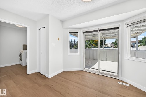 Wood-finish flooring, white painted walls, sliding glass door with window blinds, recessed laundry area, and a built-in closet - 3924 26A Avenue Nw, Edmonton, AB 