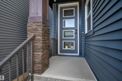 Modern front entry featuring a multi-pane door, horizontal siding, and a stone-clad pillar - 