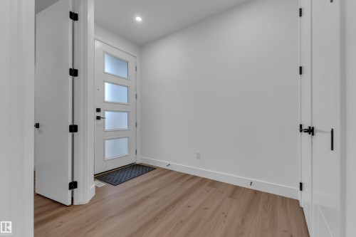 Entryway featuring a white door with frosted glass panels, wood-finish flooring, and recessed lighting - 3604 44 Avenue, Beaumont, AB 