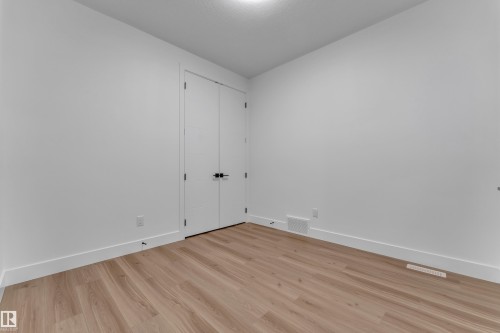 Wood-finish flooring, white walls, white trim, recessed ceiling light, and double closet doors with dark hardware - 3604 44 Avenue, Beaumont, AB 