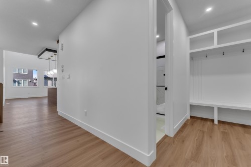 Wood-finish flooring throughout, recessed lighting, built-in storage bench with hooks, open doorway with view of additional room, and white trim - 3604 44 Avenue, Beaumont, AB 