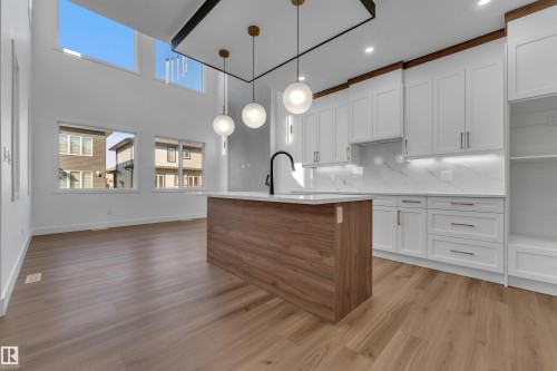 Two-story ceiling, large upper windows, wood-finish flooring, kitchen island with solid surface countertop, and white shaker cabinetry - 3604 44 Avenue, Beaumont, AB 