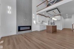 Open-concept living area featuring a modern fireplace, vaulted ceiling, and wood-finish flooring - 