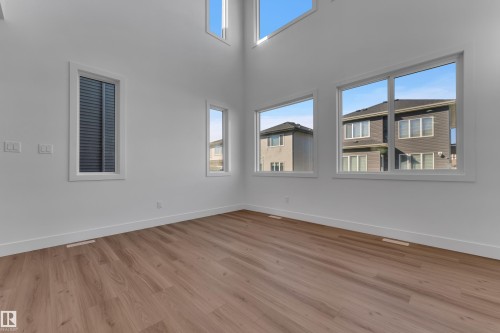 High ceilings with multiple large windows, wood-finish flooring, and white walls - 3604 44 Avenue, Beaumont, AB 