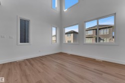 High ceilings with multiple large windows, wood-finish flooring, and white walls - 
