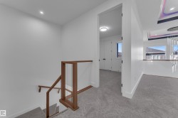 Staircase with wood-finish and glass railing, recessed ceiling lighting, and patterned carpet - 