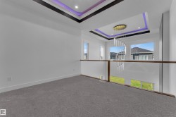 Upper-level landing with gray patterned carpeting and a glass railing - 