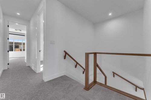 Wall-to-wall patterned carpeting, recessed ceiling lighting, a clear glass stair railing with wood-finish top and bottom rails, and a wood-finish handrail - 3604 44 Avenue, Beaumont, AB 
