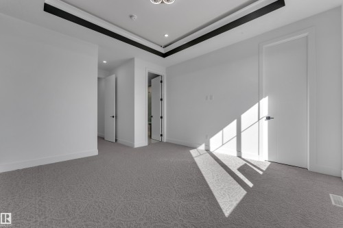 Recessed ceiling lighting, patterned carpeting, tray ceiling with contrasting accent trim, and solid interior doors with black hardware - 3604 44 Avenue, Beaumont, AB 
